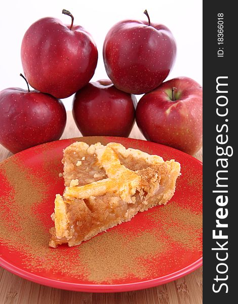 Apple Pie - a slice on a plate decorated with cinnamon and some red apples