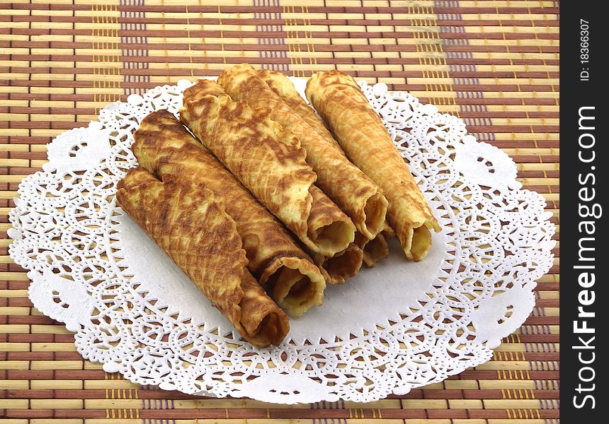 Home wafer tubules lying on a white beautiful napkin. Home wafer tubules lying on a white beautiful napkin