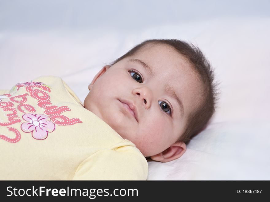 Close up of baby girl with dark hair, big dark eyes looking intensely. Close up of baby girl with dark hair, big dark eyes looking intensely.