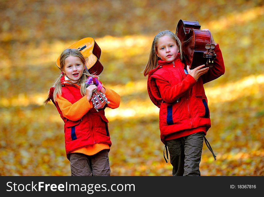 School aged girls with cello and guitar in the autumn forest. School aged girls with cello and guitar in the autumn forest