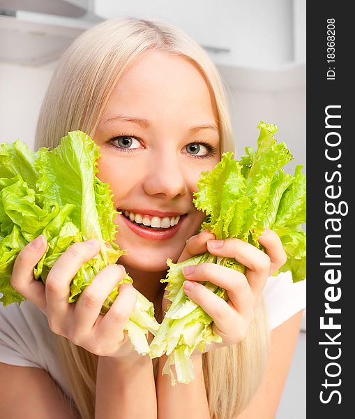 Beautiful young blond woman eating salad in the kitchen at home. Beautiful young blond woman eating salad in the kitchen at home