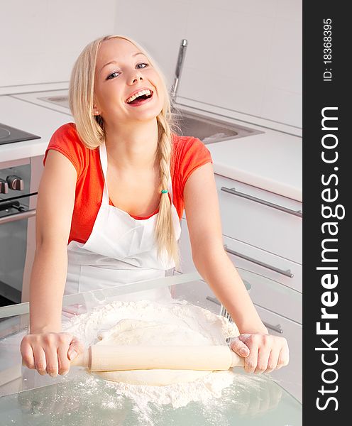 Beautiful young blond woman baking in the kitchen at home