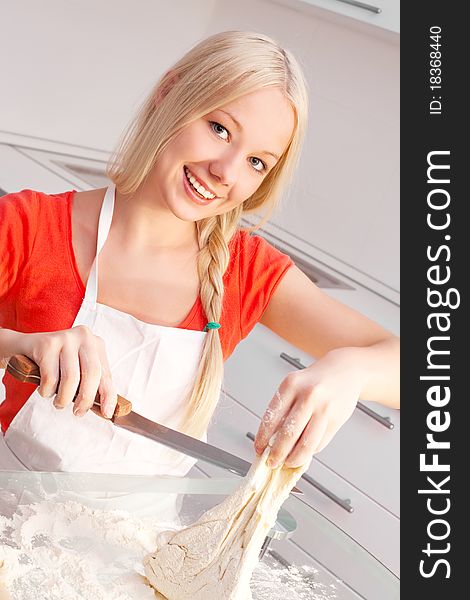 Beautiful young blond woman baking in the kitchen at home