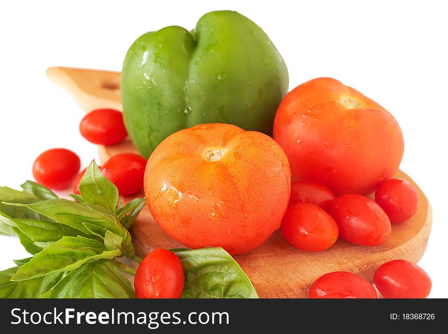 Fresh red tomatoes, green pepper and basil on wooden board isolated on white background. Fresh red tomatoes, green pepper and basil on wooden board isolated on white background