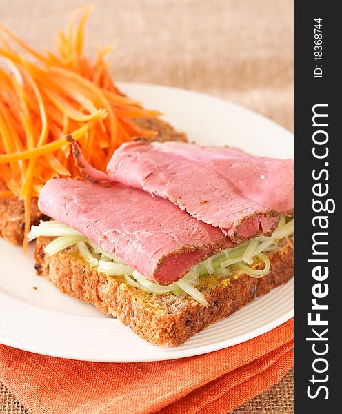 Tasty open sandwich with cucumber relish, smoked beef pastrami and sliced carrots on wholewheat bread. Tasty open sandwich with cucumber relish, smoked beef pastrami and sliced carrots on wholewheat bread