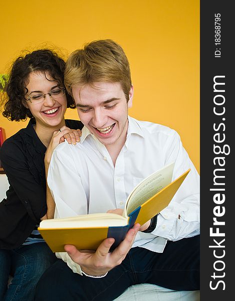 Young couple laughing while reading a book and having fun