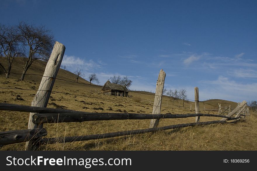 Country landscape before winter with dry grass and old house