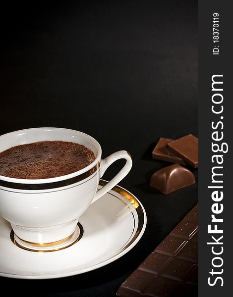 Luxury chocolate drink on white cup and milk chocolate bars, on black background. Luxury chocolate drink on white cup and milk chocolate bars, on black background