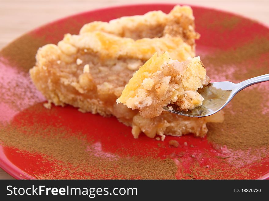 Apple Pie - a slice on a plate decorated with cinnamon being eaten with a fork