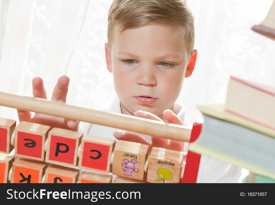Young boy put together letters on the wooden cubes and heap of books. Young boy put together letters on the wooden cubes and heap of books