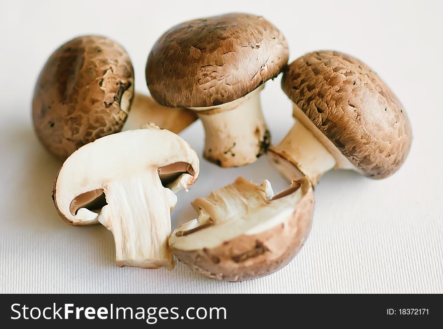 Raw mushrooms (champignons) on a white table. Raw mushrooms (champignons) on a white table