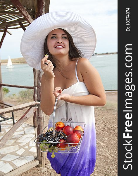 Young beautiful girl in a white hat resting in the hands of fruit. Young beautiful girl in a white hat resting in the hands of fruit