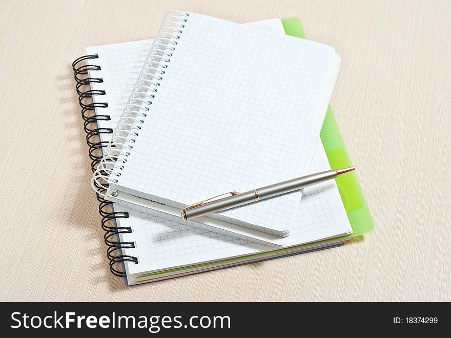 Blank spiral note pad with silver pen on wood desk. Blank spiral note pad with silver pen on wood desk