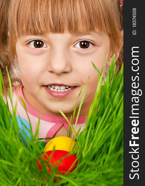 Little girl finds a multicoloured easter eggs in the tall green grass. Little girl finds a multicoloured easter eggs in the tall green grass