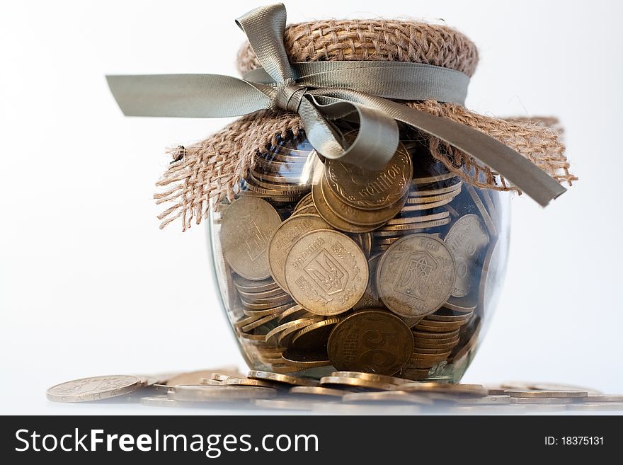 Glass jar with coins on white background