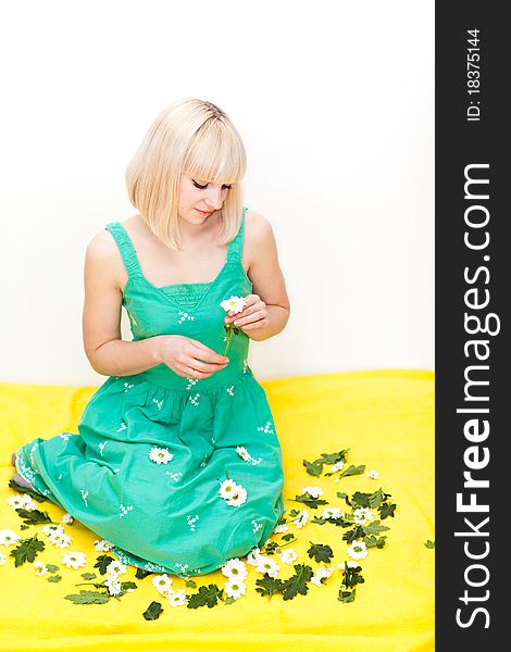 Nice young adult sitting on yellow floor with flowers in her hands and around her. Nice young adult sitting on yellow floor with flowers in her hands and around her