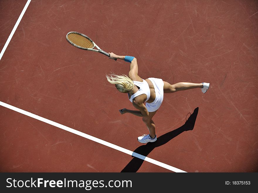 Young fit woman play tennis outdoor on orange tennis field at early morning. Young fit woman play tennis outdoor on orange tennis field at early morning