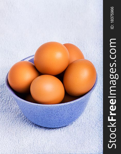 Fresh brown eggs in blue bowl