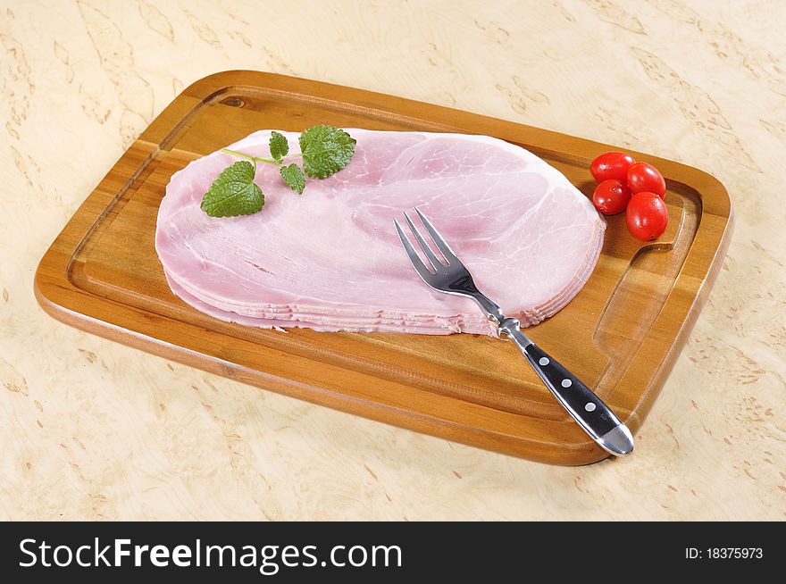 Cooked ham on a wooden board in the kitchen.