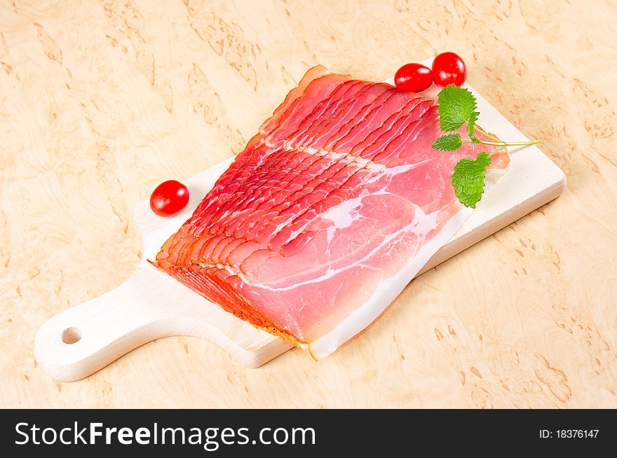 Raw ham on a wooden board in the kitchen.