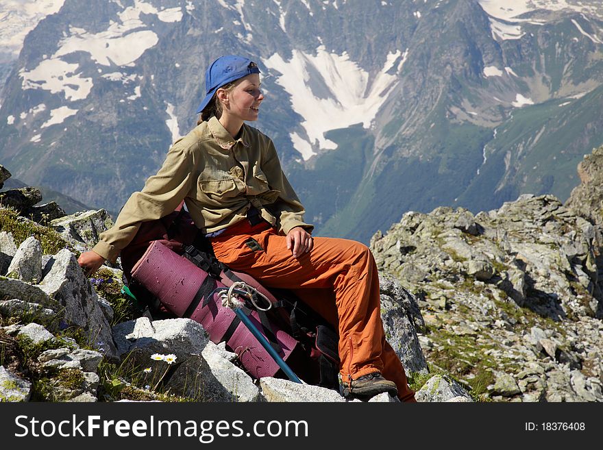 Traveler girl sitting on the backpack in mountains