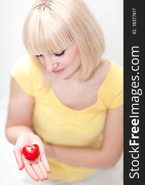 Beautiful blonde lady holding little red heart in her hand. Beautiful blonde lady holding little red heart in her hand