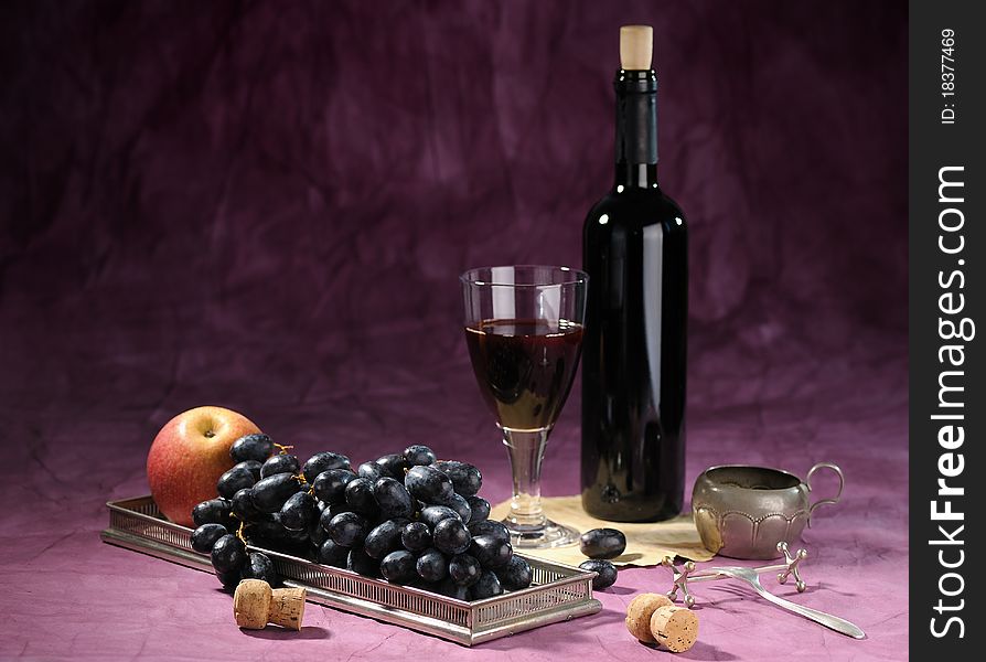 Still life with bottle of red vine and black grape on dark background. Still life with bottle of red vine and black grape on dark background