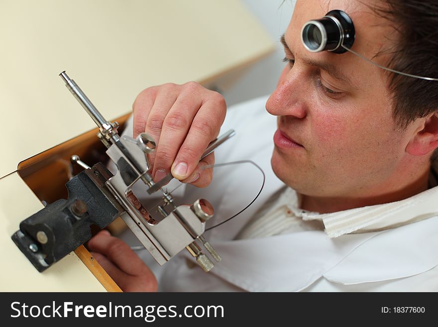 Watchmaker in his workshop repairing a wrist watch. Intentional shallow depth of field, focus on the eye.