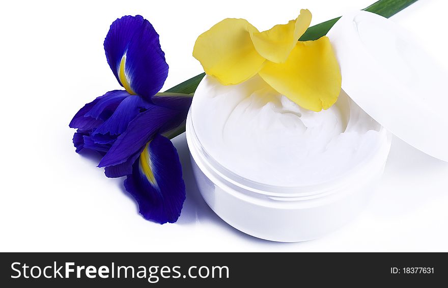 A tub of moisturizing lotion framed with Iris and Rose petals. A tub of moisturizing lotion framed with Iris and Rose petals