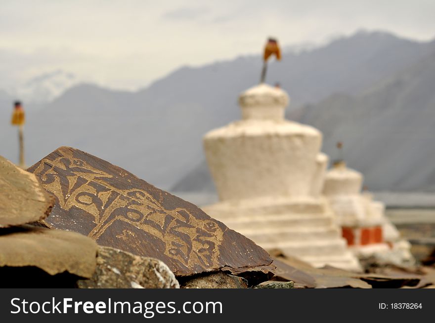 Mani stone containing the Buddhist prayer Om Mani Padme Hum and white chortens in Ladakh, India