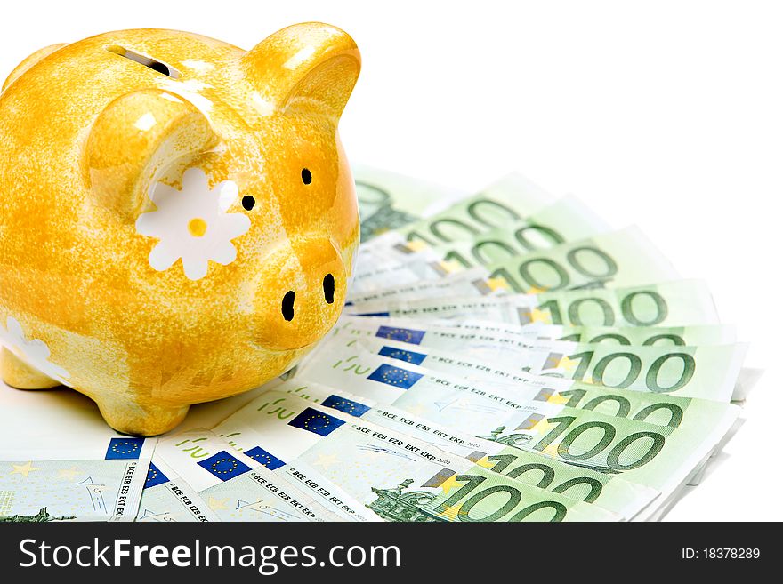 Yellow ceramic piggy bank on a pile of European banknotes, isolated on white. Yellow ceramic piggy bank on a pile of European banknotes, isolated on white