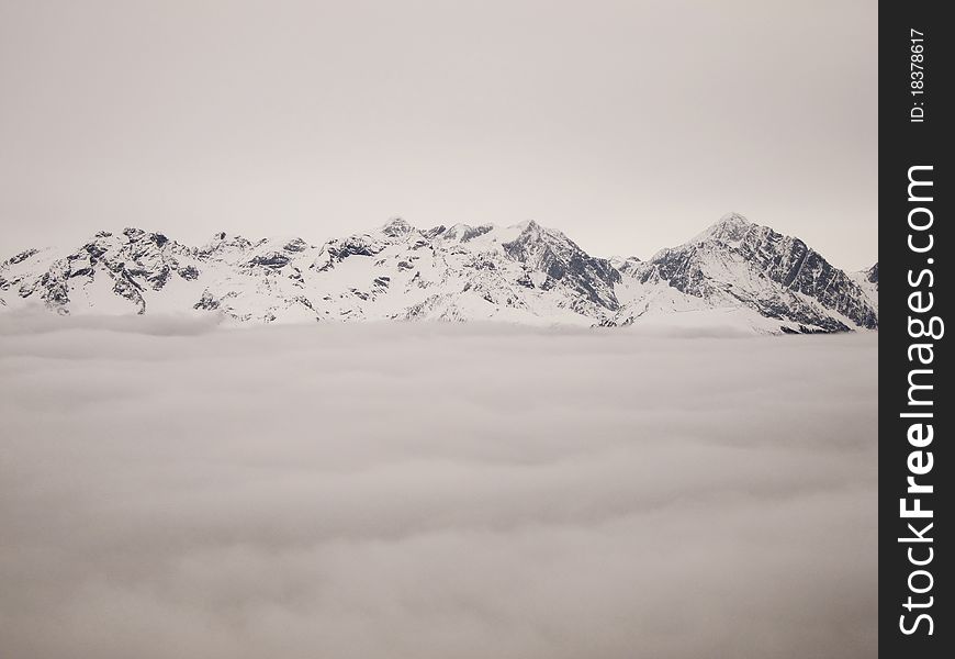 Top of snowy mountains over the clouds