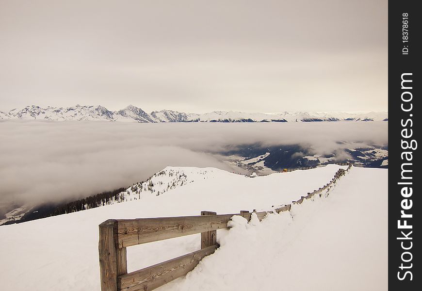 Fence and snow above clouds in the alps