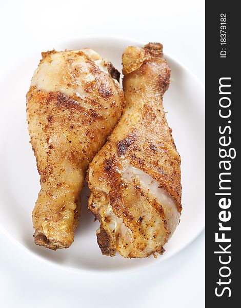 Two roasted chicken legs on plate on white background