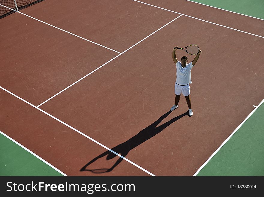 Young man play tennis outdoor on orange tennis field at early morning