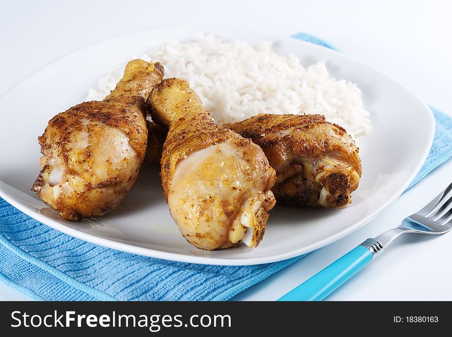 Roasted chicken legs with boiled rice on a plate