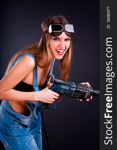 Girl with a drill in building overalls