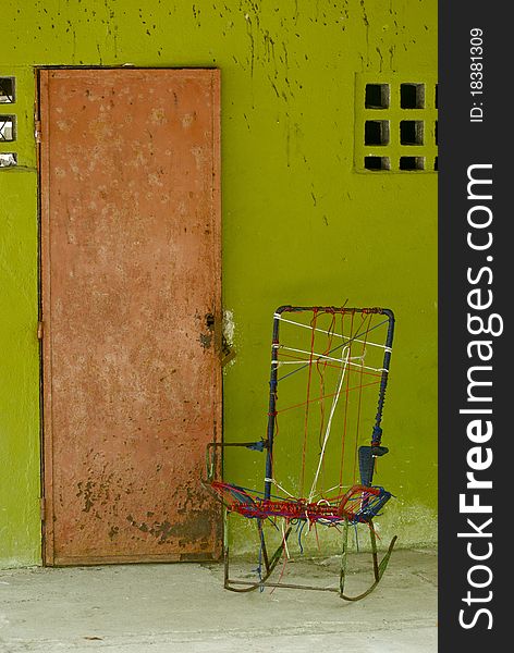 A front door of a bright green costa rican house with a home-made rocking chair by the door. A front door of a bright green costa rican house with a home-made rocking chair by the door.