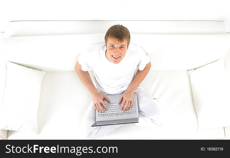 Portrait of a young man relaxing on couch while using a laptop