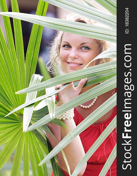 Young beautful woman looking through palm tree leaves. Young beautful woman looking through palm tree leaves