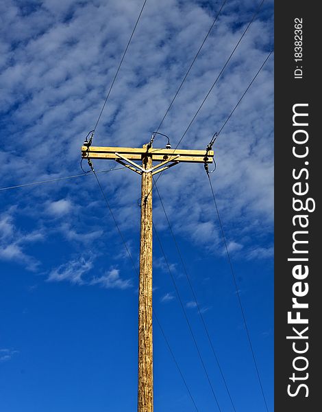 A power pole with electrical transmission wires and the sky in the background. A power pole with electrical transmission wires and the sky in the background.