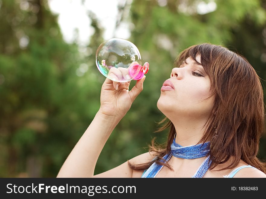Attractive girl inflating soap bubbles outdoors