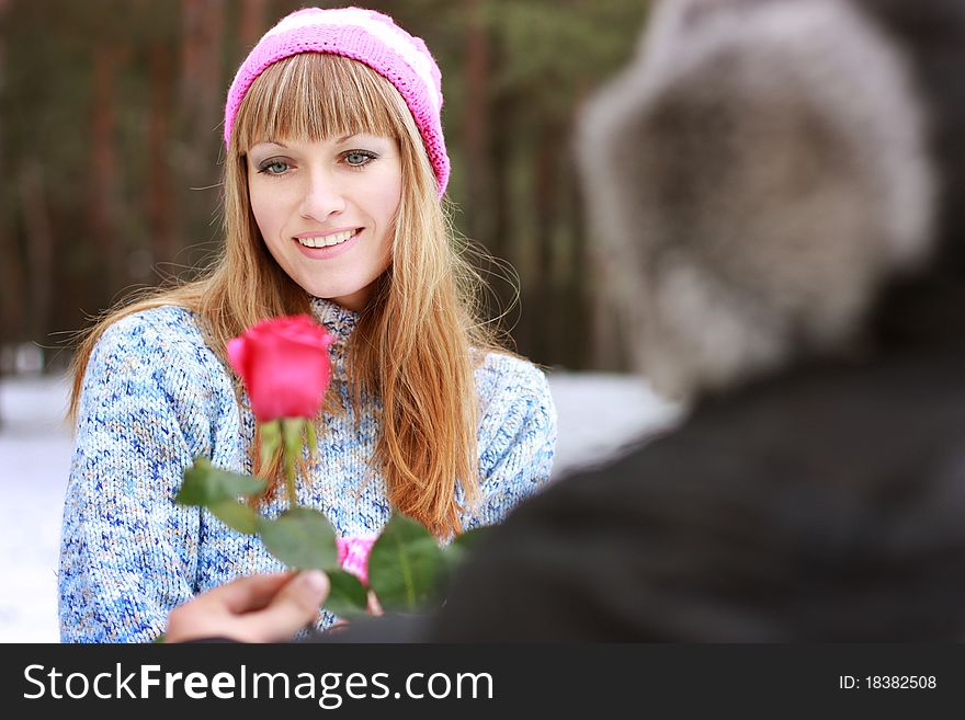 Man handing over a single red rose to young woman