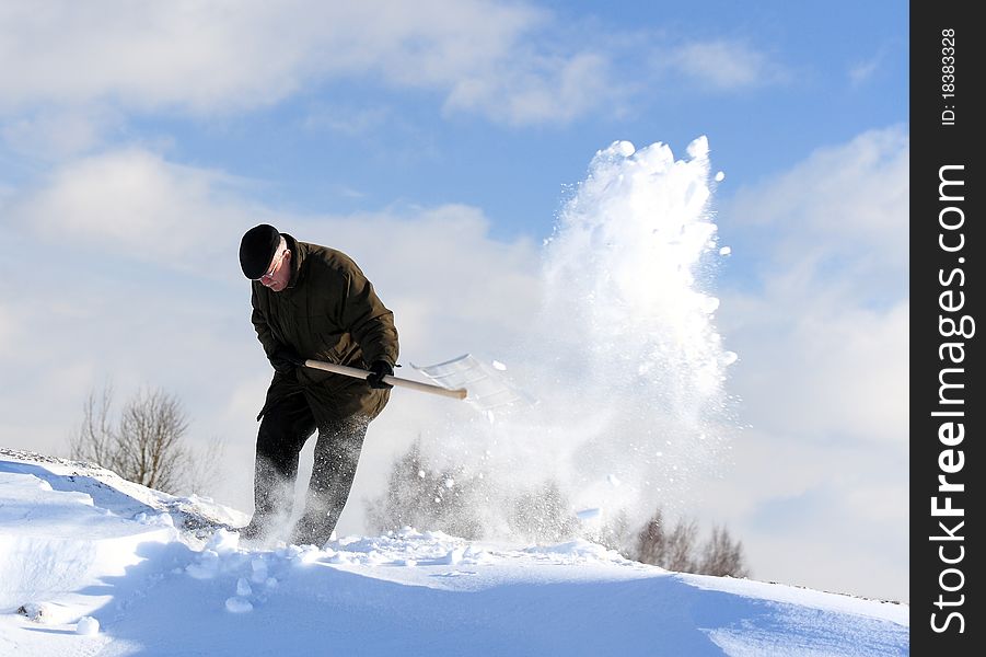 A man with a shovel removing snow from a roof. A man with a shovel removing snow from a roof