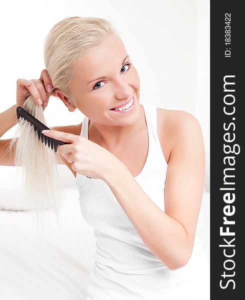 Beautiful young blond woman brushing her hair and smiling. Beautiful young blond woman brushing her hair and smiling