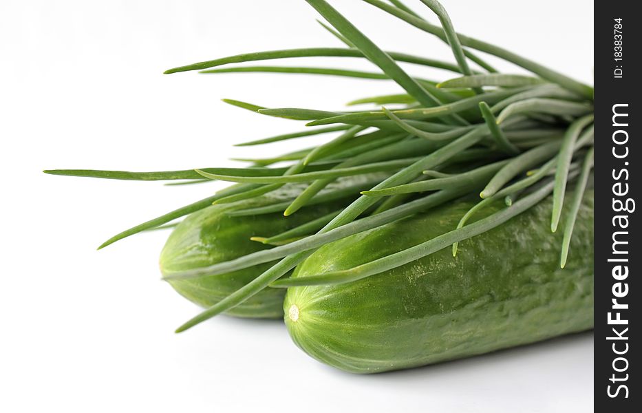 A bunch of green onions and cucumbers on a white background