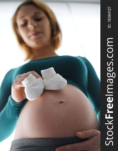 Pregnant woman holding baby shoes