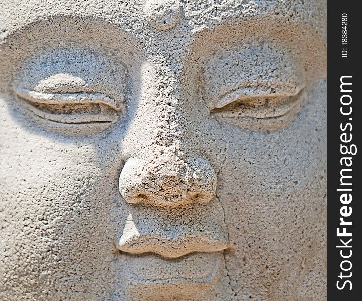 Close-up of ancient stone Buddha statue with strong texture and cracks. Close-up of ancient stone Buddha statue with strong texture and cracks