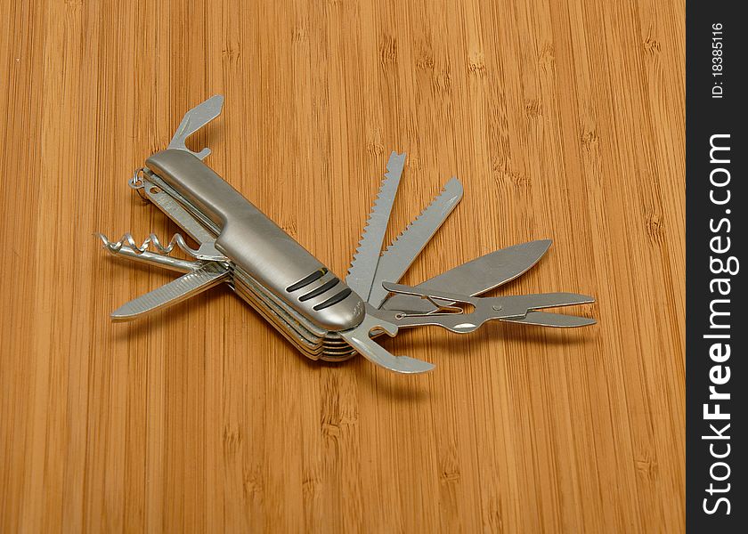 Swiss knife with all open blades on a wooden surface