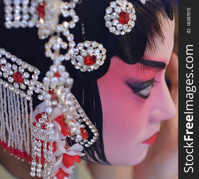 A chinese opera actress is painting her face backstage